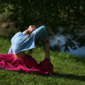 Beautiful young woman in red skirt practicing Yoga asana in nature