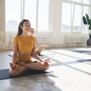 Smiling women doing yoga exercise in gym